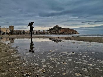 Man standing on wet shore during rainy season