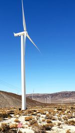 Wind turbines on land against clear sky
