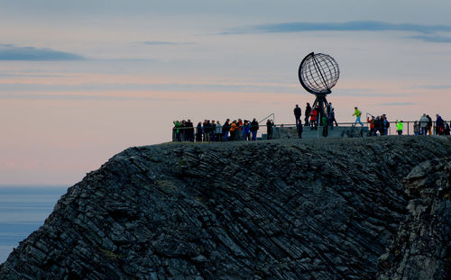 Low angle view of people on mountain against sky during sunset