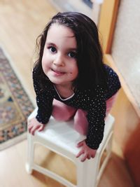 Portrait of smiling girl sitting on table at home