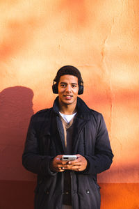 Portrait of smiling young man standing against wall
