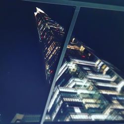 Low angle view of illuminated skyscraper against clear sky at night