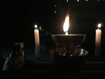 Close-up of lit tea light candles in darkroom