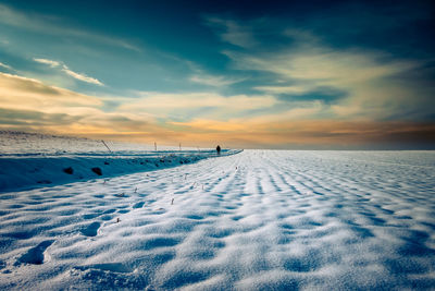 Scenic view of snow covered field against sky during sunset