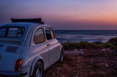 View car parked on beach against sky during sunset