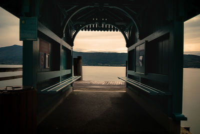 Empty bridge over sea against sky during sunset