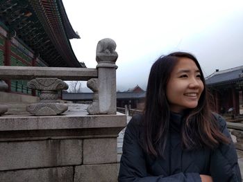 Happy young woman standing by traditional building