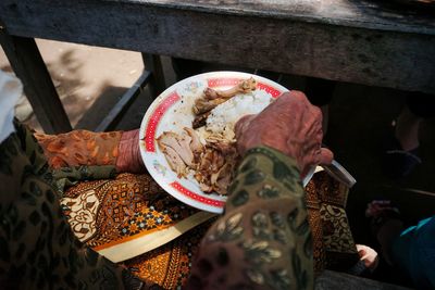 Old woman eating food with right hand