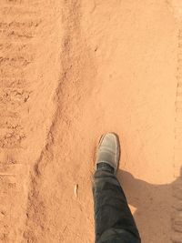 Low section of man standing on sand at beach