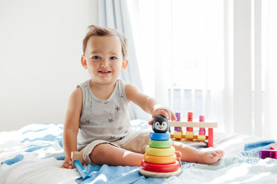 Cute boy playing with toy on bed