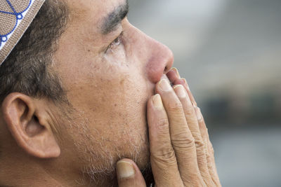 Close-up of mature man praying while sitting at mosque