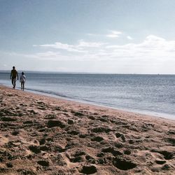 Man walking on beach against sky