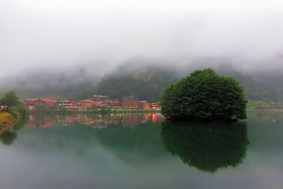 Scenic view of lake by trees and buildings against mountain