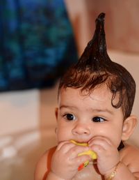 Close-up of cute baby girl playing with rubber duck while bathing in bathtub