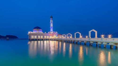 Illuminated building against blue sky at night