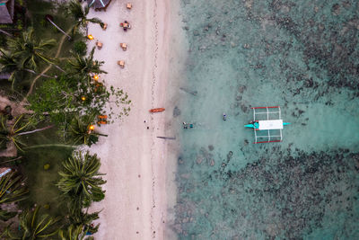 In the photo, a vibrant tropical boat near a beautiful beach or rocky shore.