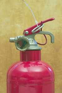 Close-up of fire extinguisher against yellow wall