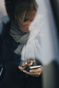 Mature woman using mobile phone sitting car