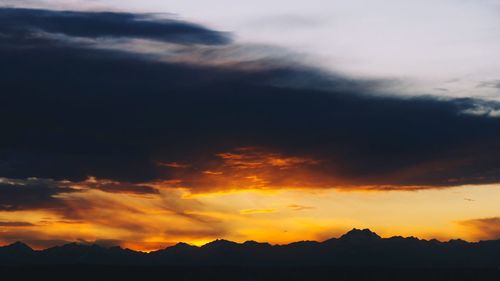 Scenic view of silhouette mountains against dramatic sky