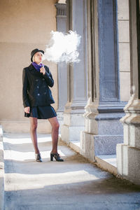 Young woman smoking while standing at corridor