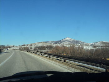 Road by mountain against clear blue sky