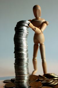 Close-up of figurine with stacked coins on white background