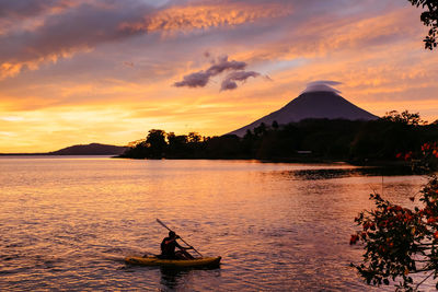 Man on boat against sky during sunset