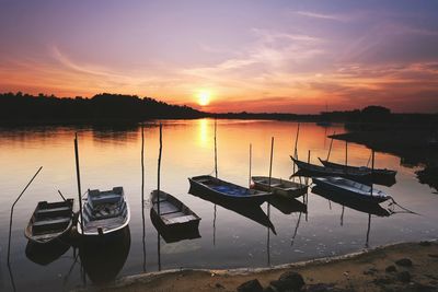 Boats moored in lake against sky during sunset