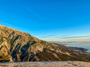 Scenic view of sea and mountains against blue sky