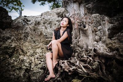 Portrait of woman sitting against tree