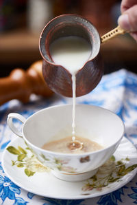 Close-up of person pouring coffee in cup