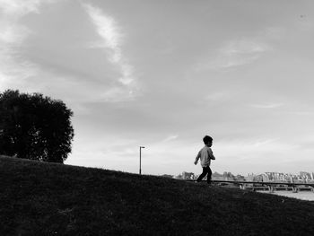 Boy walking on field against sky