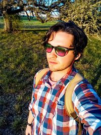 Portrait of young man wearing sunglasses standing on field