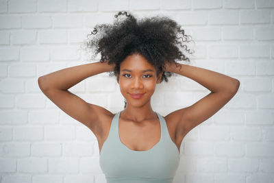 Portrait of young woman standing against wall