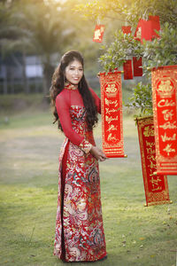 Portrait of young woman standing against red wall