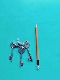 High angle view of pencils on table against blue background