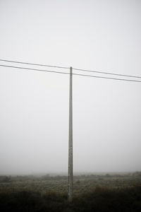 Electricity pylon on field against clear sky