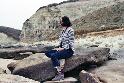 Rear view of woman sitting on rock