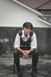 Side view of young man sitting on street