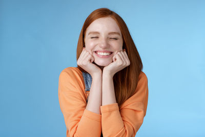 Portrait of a smiling young woman against blue background