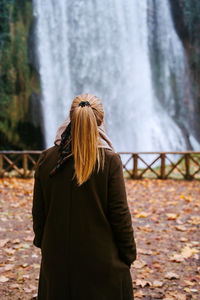 Rear view of woman standing against trees during winter