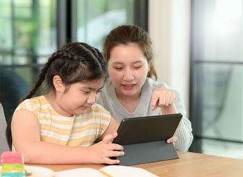 Asian girl studying privately with tutor at home, siblings teaching homework, online learning.