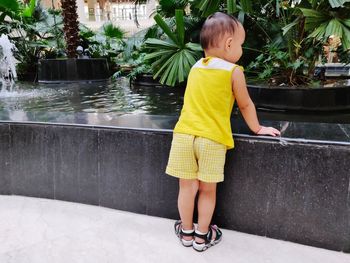 Rear view of baby girl looking at fountain while standing in park