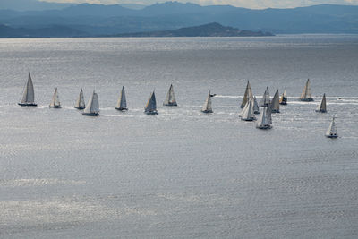 Sailboats in sea against mountains