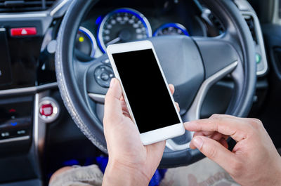 Cropped hands of man using mobile phone in car