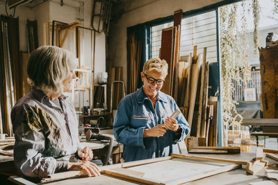 Smiling senior female carpenters talking while working at workshop