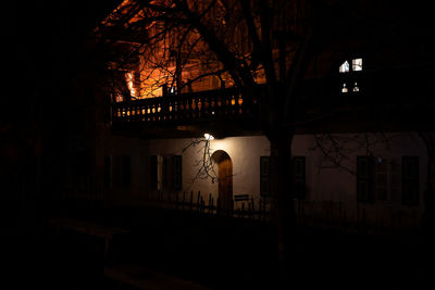 Illuminated street light by building at night