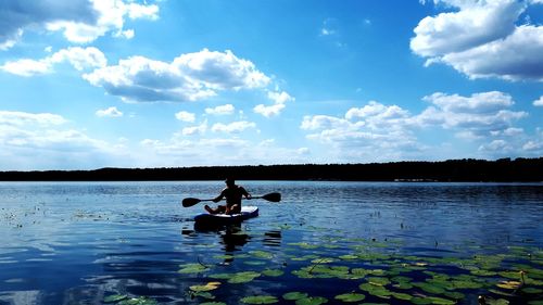 Man sitting on boat in lake against sky