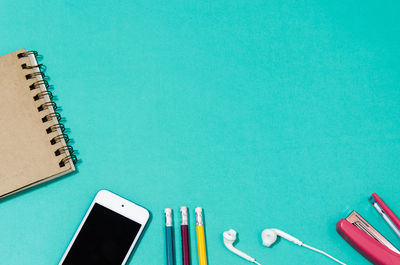 High angle view of smart phone and books against blue background