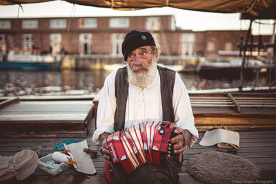 Portrait of man holding hat sitting outdoors